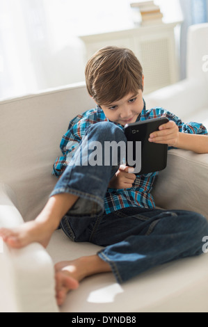 Hispanic boy using digital tablet in armchair Stock Photo