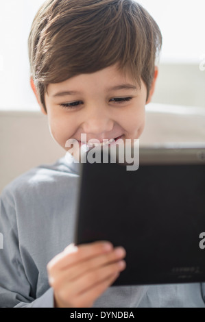 Hispanic boy using digital tablet on sofa Stock Photo