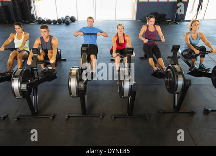 People using rowing machines in gym Stock Photo