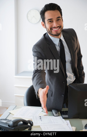 Mixed race businessman offering handshake in office Stock Photo