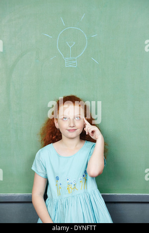 Smart girl has an idea with lightbulb over her head drawn on a chalkboard Stock Photo