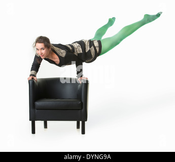 Athletic hispanic young woman balancing on black chair Stock Photo