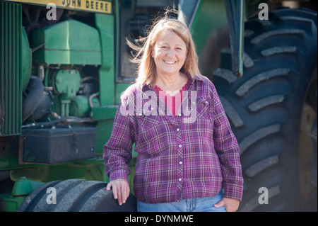 Female farmer in plaid purple shirt standing in front of tractor Gettysburg PA Stock Photo