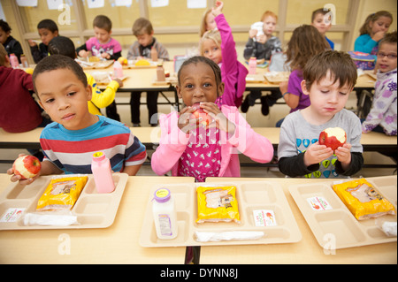 Elementary school children sitting at tables eating apples in a cafeteria Hagerstown, Maryland Stock Photo