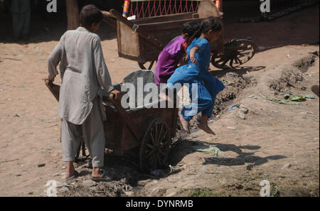 ISLAMABAD, PAKISTAN-APRIL 23: Afghan refugee girls play as a boy pushes his hand cart in the slum area in the outskirts of Islamabad, Pakistan. More than five millions of Afghan refugees fled their homeland since Soviet invasion in 1970s. Some 3.6 million Afghan refugees have been repatriated to Afghanistan from Pakistan since March 2002, under a tripartite agreement between the UN Refugee Agency (UNHCR) and the governments of Pakistan and Afghanistan. More than 1.6 million Afghan refugees are still living in Pakistan, especially in camps and slums areas and not returning to their homeland due Stock Photo