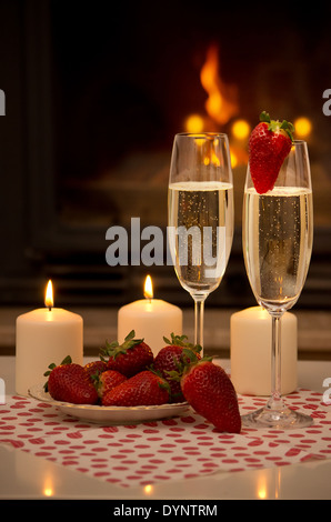 Champagne, strawberries, candles and a romantic evening by the fireplace. Stock Photo