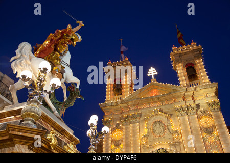 Statue of St George slaying the dragon mounted on a pedestal during the town feast of St George's Basilica in Gozo in Malta. Stock Photo