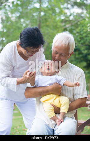 asian baby crying while being comforted by grandparents Stock Photo