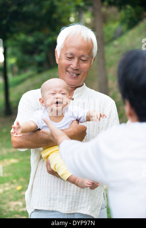 asian baby crying while being comforted by grandparents Stock Photo