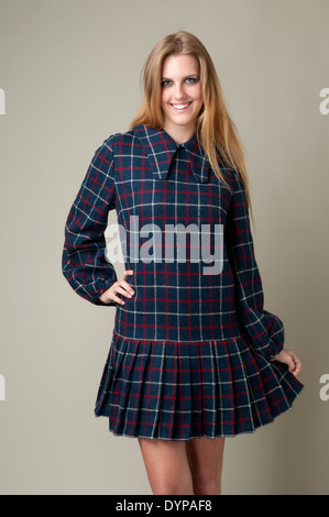 A blonde hair woman, Caucasian woman, female model wearing a 60s dress, posing in a studio, a 60s vintage fashion concept Stock Photo