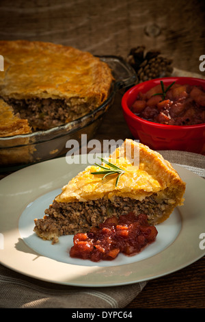Slice of traditional pork meat pie Tourtiere with apple and cranberry chutney from Quebec, Canada. Stock Photo