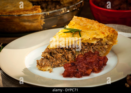 Slice of traditional pork meat pie Tourtiere with apple and cranberry chutney from Quebec, Canada. Stock Photo