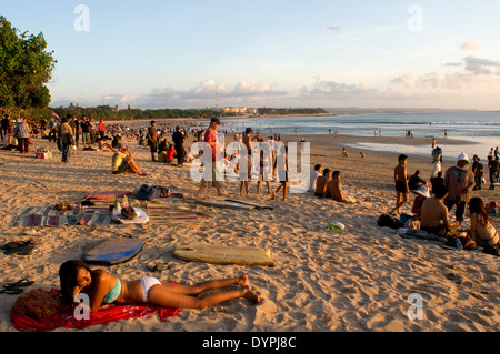 At dusk everyone gathers to watch the sunset with a beer on the beach of Kuta. Surfers on the beach of Kuta. Surfing lessons. Stock Photo