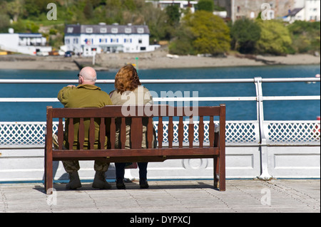 Couple sitting on bench at end of Bangor Pier on the Menai Strait at Bangor Gwynedd North Wales UK Stock Photo