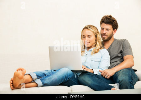 Happy young couple at home using laptop computer Stock Photo