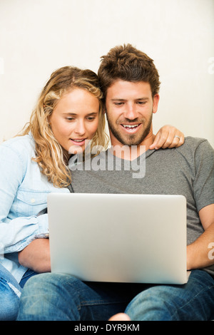 Happy young couple at home using laptop computer Stock Photo