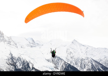 A tourist, tandem paraglides with a guide above the valley of Chamonix Mont-Blanc, taking off from Planpraz. Stock Photo