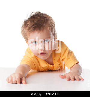 Portrait of a cute cheerful little boy, who is smiling while sitting at table, isolated over white Stock Photo