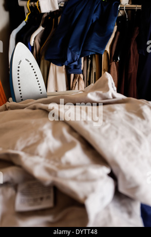 A pile of bedlinen for ironing with an electric iron visible amongst the linen. Stock Photo
