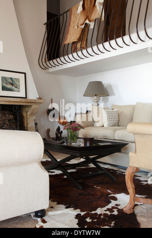 Sitting area with ponyskin rug beneath wrought iron balustrade to gallery, Villa in St Tropez Stock Photo