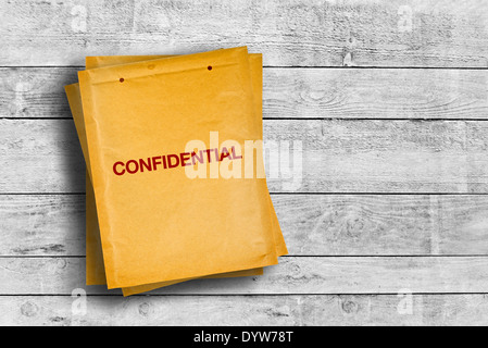 Confidential stamp on yellow envelope placed on wooden table Stock Photo