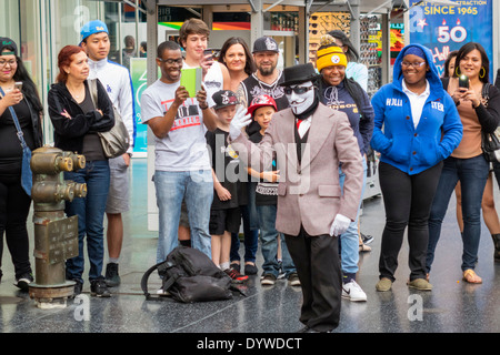 California,LA,Los Angeles,Hollywood Boulevard,movie industry,Hollywood Walk of Fame,street performer,busking tips,costume,Anonymous mask,audience,mime Stock Photo