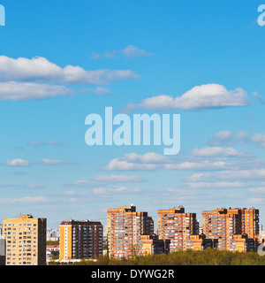 white clouds in blue sky over brick apartment houses in spring Stock Photo