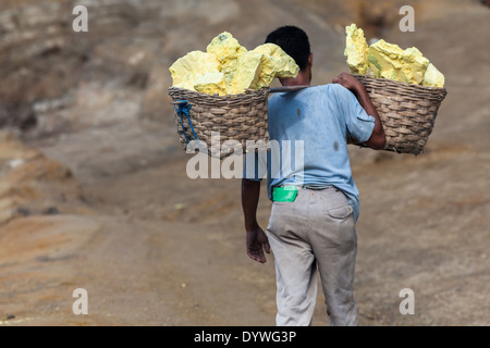 Man carrying baskets laden with blocks of sulfur, Kawah Ijen, Banyuwangi Regency, East Java, Indonesia Stock Photo