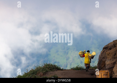 Man carrying baskets laden with blocks of sulfur, area of Kawah Ijen, Banyuwangi Regency, East Java, Indonesia Stock Photo