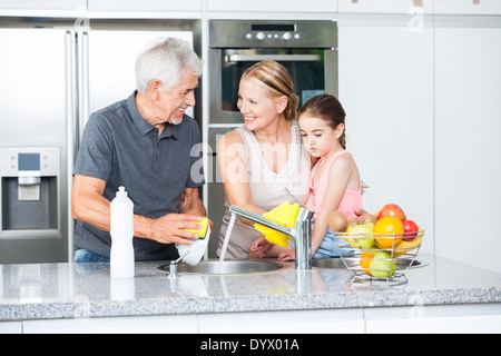 Grandparents and little girl washing dishes Stock Photo