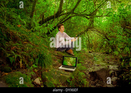 man using tablet and laptop in the jungle Stock Photo