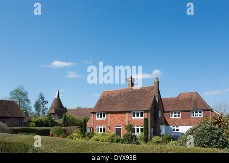 A beautiful country cottage in Lamberhurst Kent with spring tulips in the garden and Kentish Oast house in the background Stock Photo