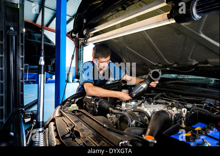Apprentice mechanic under car hood Stock Photo