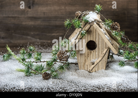 birdhouse and christmas tree brunch decoration over rustic wooden background. vintage country style picture with snow Stock Photo