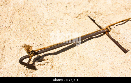 Old rusty anchor embroidered on the beach. Stock Photo