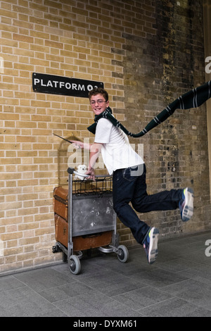 Harry Potter fan jumping at Platform 9 3/4 at King's Cross Station in London United Kingdom Stock Photo