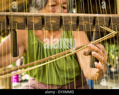 April 25, 2014 - Mae Chan, Chiang Rai, Thailand - An elderly woman weaves papyrus reed matts by hand at her family home in Mae Chan, Chiang Rai province, Thailand. Families in Chiang Rai province still make woven reed mats by hand. The mats are used around the house as an impromptu table, and farmers as something to spread out on the ground during lunch, like a picnic blanket. Some families use them as mattresses to sleep on. They cost anywhere from 15Baht (.50Â¢ US) to 150Baht ($5.00 US) depending on size. (Credit Image: © Jack Kurtz/ZUMAPRESS.com) Stock Photo