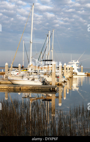 Fluffy white clouds (Altocumulus floccus) reflected in the dark water of the Fernandina Beach harbor and boat docks, USA. Stock Photo