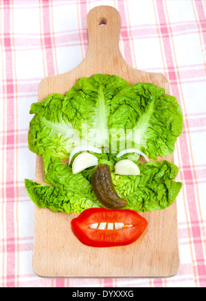 Funny face composition made of vegetables on wooden board. Stock Photo