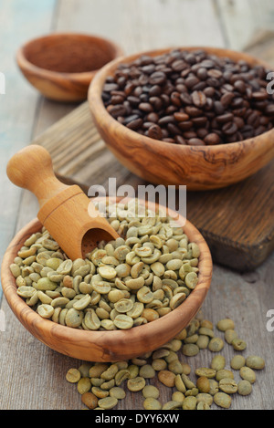 Green and roasted coffee beans in wooden bowl closeup Stock Photo