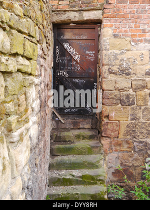 Derelict / run-down stone steps and doorway, with graffiti, in rear yard of commercial premises. Stock Photo