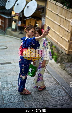 Asian women in traditional kimonos take a self-portrait using a cel phone near the Kiyomizu Temple. Stock Photo