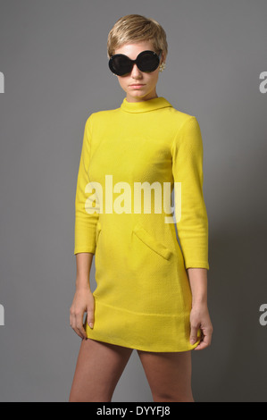 A red hair woman,Caucasian woman, female model wearing a mod 60s dress, round sunglasses, a 60s vintage fashion concept Stock Photo