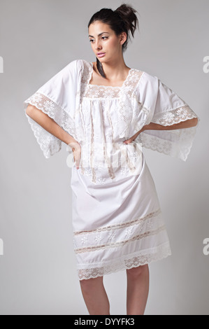A black hair woman with ponytail, multiracial female model wearing a romantic floral 70s white lace dress posing Stock Photo