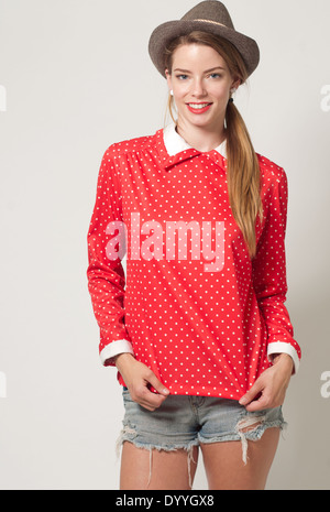 A blonde hair woman in pony tail, Caucasian female model wearing a red polka dot top and hat, a vintage fashion concept Stock Photo