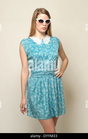 A long blonde hair woman ,Caucasian female model wearing a retro 80s green floral dress and cat eye sunglasses posing Stock Photo