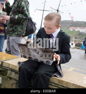 A smartly dressed boy eating take away fish and chips from the famous Magpie café  at the Whitby Goth Week End spring 2014 Stock Photo