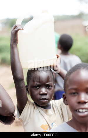 Children collect water from an unclean government water source in the Kosovo slum area of Kampala city in Uganda. Stock Photo