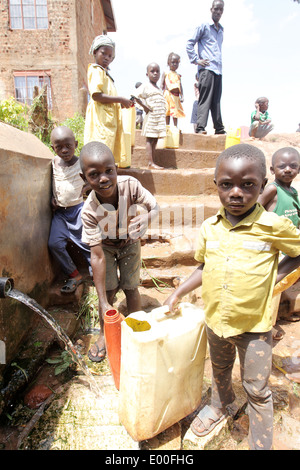 Children collect water from an unclean government water source in the Kosovo slum area of Kampala city in Uganda. Stock Photo