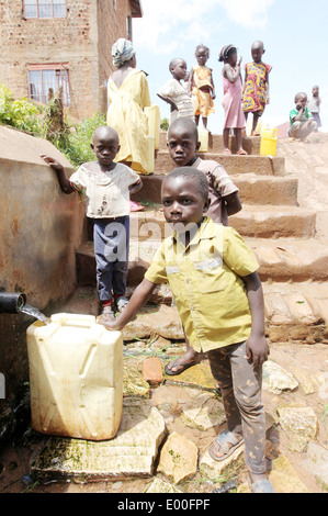 Children collect water from an unclean government water source in the Kosovo slum area of Kampala city in Uganda. Stock Photo